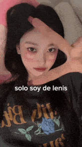 a girl wearing a black shirt that says solo soy de lenis makes a peace sign