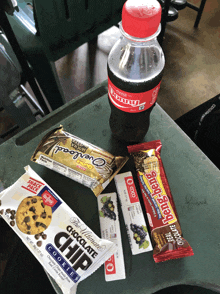 a bottle of coke sits on a table with snacks