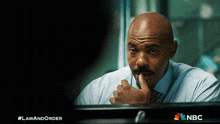 a man with a mustache is looking at himself in a mirror with a nbc logo on the bottom