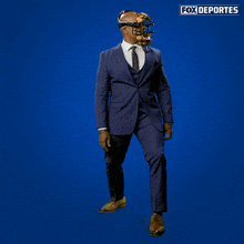 a man in a suit and tie is holding a baseball helmet in front of a blue background with fox deportes written on it