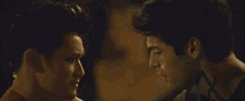 a close up of a man holding another man 's head in a dark room .