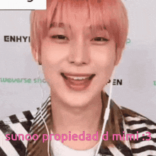 a man with pink hair is wearing headphones and smiling while wearing a striped shirt .