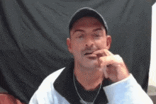 a man with a mustache is wearing a hat and necklace