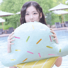 a girl is holding a sprinkle shaped float in front of her face