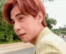 a man with red hair is standing on the side of a road