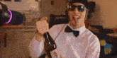 a man in a bow tie and sunglasses is holding a bottle of champagne .