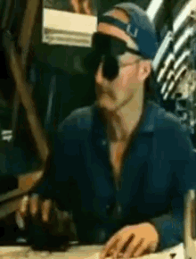 a man wearing sunglasses and a blue hat with the letter u on it