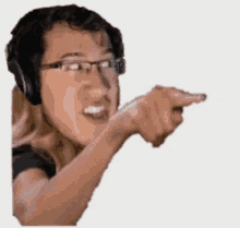 a man wearing headphones and glasses is pointing his finger at something .