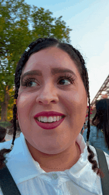 a woman with braids and a white shirt smiles