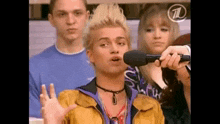 a man is singing into a microphone while a group of people watch .