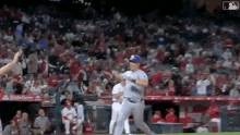 a baseball player is running towards the dugout during a game while a crowd watches .