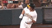 a baseball player wearing an athletics jersey is running towards home plate