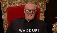 a man wearing glasses and a suit is sitting in a chair with the words wake up written below him