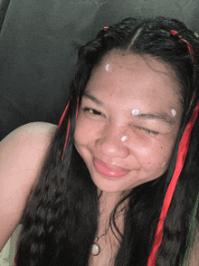 a woman with red and green ribbons in her hair is smiling with her eyes closed