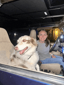 a woman sits in the driver 's seat with a dog
