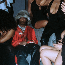 a man wearing a fur hat sits in a crowd of people