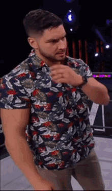 a man in a floral shirt is standing in a ring