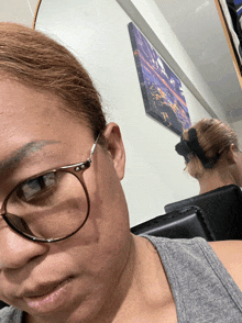 a woman wearing glasses is looking at herself in a mirror