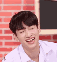 a young man is smiling with his eyes closed and his mouth open .