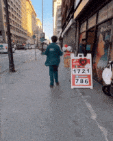 a man walking down a sidewalk with a sign that says 1721 786