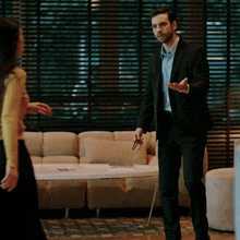 a man in a suit is holding a pair of glasses and talking to a woman