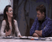 a man and a woman sit at a table talking