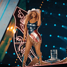 a woman wearing a cowboy hat and a patriotic outfit stands on a stage