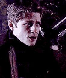a man is holding a gun in his hand in a dark room .