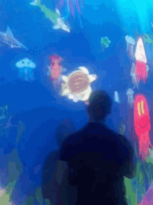 a man stands in front of a display of sea creatures including a turtle and jellyfish