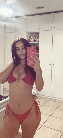 a woman in a red bikini takes a picture of herself in the mirror