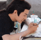a man is sitting at a table looking at his cell phone