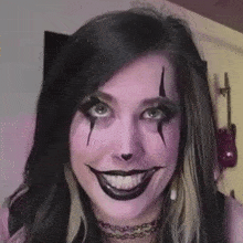 a woman with purple makeup on her face is smiling and making a funny face .