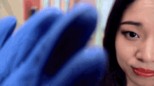 a woman wearing a blue glove is looking at the camera