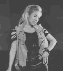 a black and white photo of a woman wearing a vest and a ponytail .