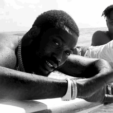 a black and white photo of a shirtless man laying on the beach