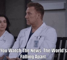 a man in a lab coat is sitting next to a woman and says you watch the news the world 's falling apart