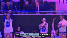 a man in a suit and tie is sitting in the stands watching a basketball game