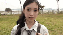a girl in a striped shirt and tie is standing in a grassy field