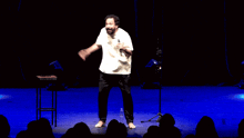 a man in a white shirt is dancing on stage in front of a crowd