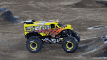 a monster truck that looks like a school bus is driving on a dirt road