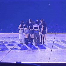 a group of girls are standing on a stage in a circle .