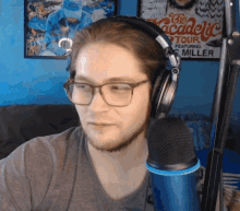 a man wearing headphones and glasses stands in front of a microphone in front of a sign that says the academic tour