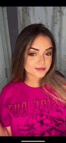 a woman wearing a pink t-shirt that says ' tue 30 ' on it