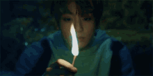 a young boy is holding a lit match in his hand in the dark .
