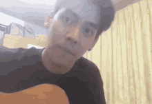 a man is playing a guitar in a living room and making a funny face .