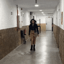a woman walks down a hallway with a fire extinguisher on the wall