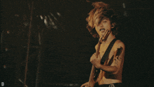 a shirtless man playing a guitar with the letter d in the lower right corner