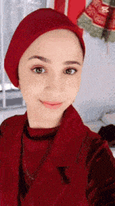 a woman wearing a red turban is taking a selfie .
