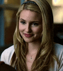 a woman with long blonde hair wearing a headband and a cross necklace