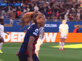 a female soccer player stands on the field in front of a sign that says dep